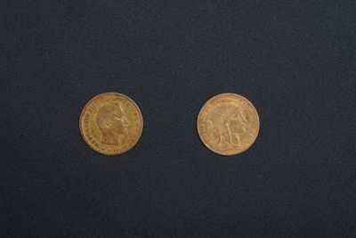 deux pièces d'or posées sur une surface noire, l'une à côté de l'autre