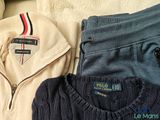 three sweaters and a sweater jacket on a bed