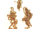 deux chaînes en or et un collier posés sur une surface blanche