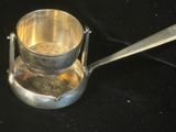 une tasse en argent contenant une cuillère, posée sur une surface noire