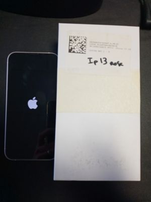un iPhone noir posé à côté d'une feuille de papier sur laquelle figure un code QR