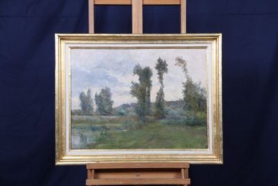 une peinture à l'huile représentant un paysage, posée sur un chevalet, avec un fond bleu