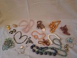 many different necklaces and bracelets laid out on a table