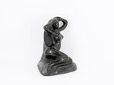 statue of a woman sitting on a rock with her hands on her head