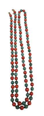 a close up of a long necklace with red and green beads