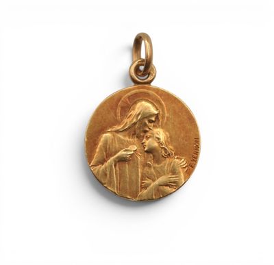 une médaille d'or représentant Jésus tenant un enfant dans ses bras