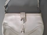 white leather purse with silver hardware on a grey surface