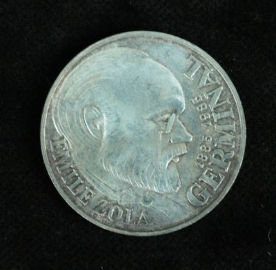 an old silver coin with a man ' s face on it on a black surface