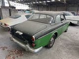 a green and black car parked in a garage next to other cars