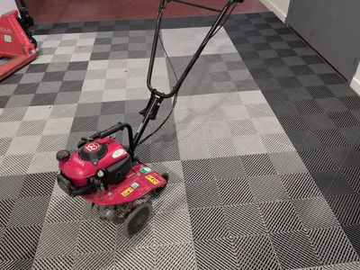 a small pink lawn mower on the floor in a garage