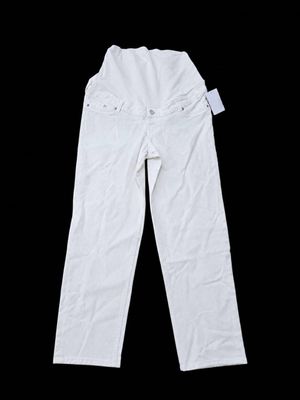Le pantalon est blanc et comporte des boutons sur le côté.