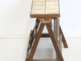 a small wooden stool with a tile top on a white floor