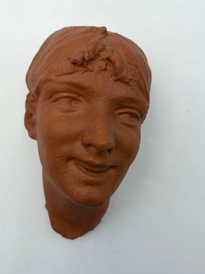 a clay sculpture of a woman ' s face on the wall