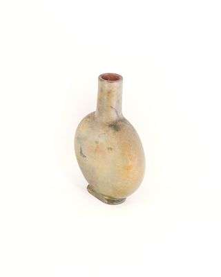 un petit vase posé sur une surface blanche