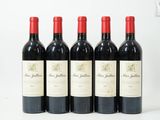 quatre bouteilles de vin rouge sont alignées sur une surface blanche