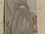 an old photo of a woman in a long dress sitting on a chair