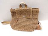 beige straw handbag with leather strap on white background