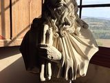 une statue représentant un homme assis sur une table devant une fenêtre