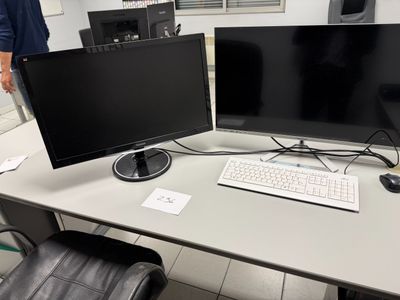 two monitors and a keyboard on a desk in a room