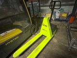 un chariot élévateur jaune garé dans un entrepôt à côté d'une palette