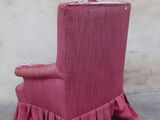 a pink chair with ruffles on it in front of a wall