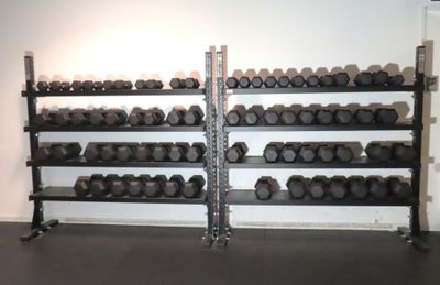 a rack of dumbs in a gym room with a wall of dumbs