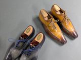two pairs of men ' s shoes sitting on a table next to a pair of shoes