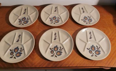 six white plates with blue flowers on them sit on a wooden table