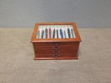 a small wooden box with pens in it on a table
