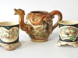 three cups and a teapot sitting next to each other