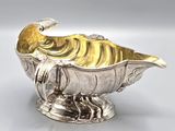 an image of a silver and gold fish shaped dish on a stand