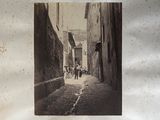 a black and white photo of people walking down a narrow street