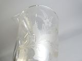 un pichet en verre transparent orné d'un motif floral