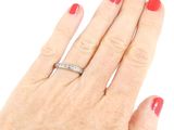 a woman ' s hand with a red manicure holding a diamond ring