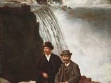 un tableau représentant deux hommes assis sur un rocher devant une cascade