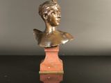 a bronze bust of a woman on a wooden pedestal