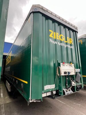 a large green container truck parked in a parking lot