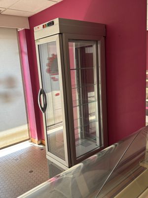 a refrigerator in the middle of a room with a pink wall