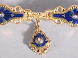 une broche bleue et dorée ornée d'un diamant en forme de goutte