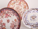 three plates with floral designs on them sitting on a white surface
