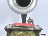 un gramophone argenté posé sur un socle recouvert d'un tissu rouge