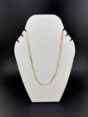 a white mannequin with a gold chain on it