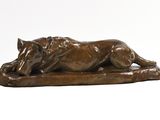 une statue en bronze représentant un chien couché sur un rocher