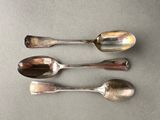 three silver spoons sitting on top of a table next to each other