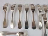 many forks and spoons laid out on a table