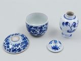 a blue and white vase, a bowl, and a cup on a table