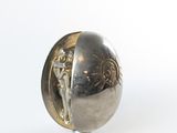 a silver ball with a statue on it on a white surface
