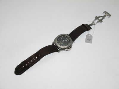une image représentant une montre posée sur une surface blanche, à laquelle est attachée une étiquette
