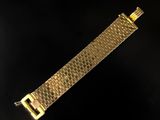 a close up of a gold bracelet on a black background