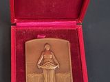 une médaille d'or dans une boîte rouge posée sur une table noire